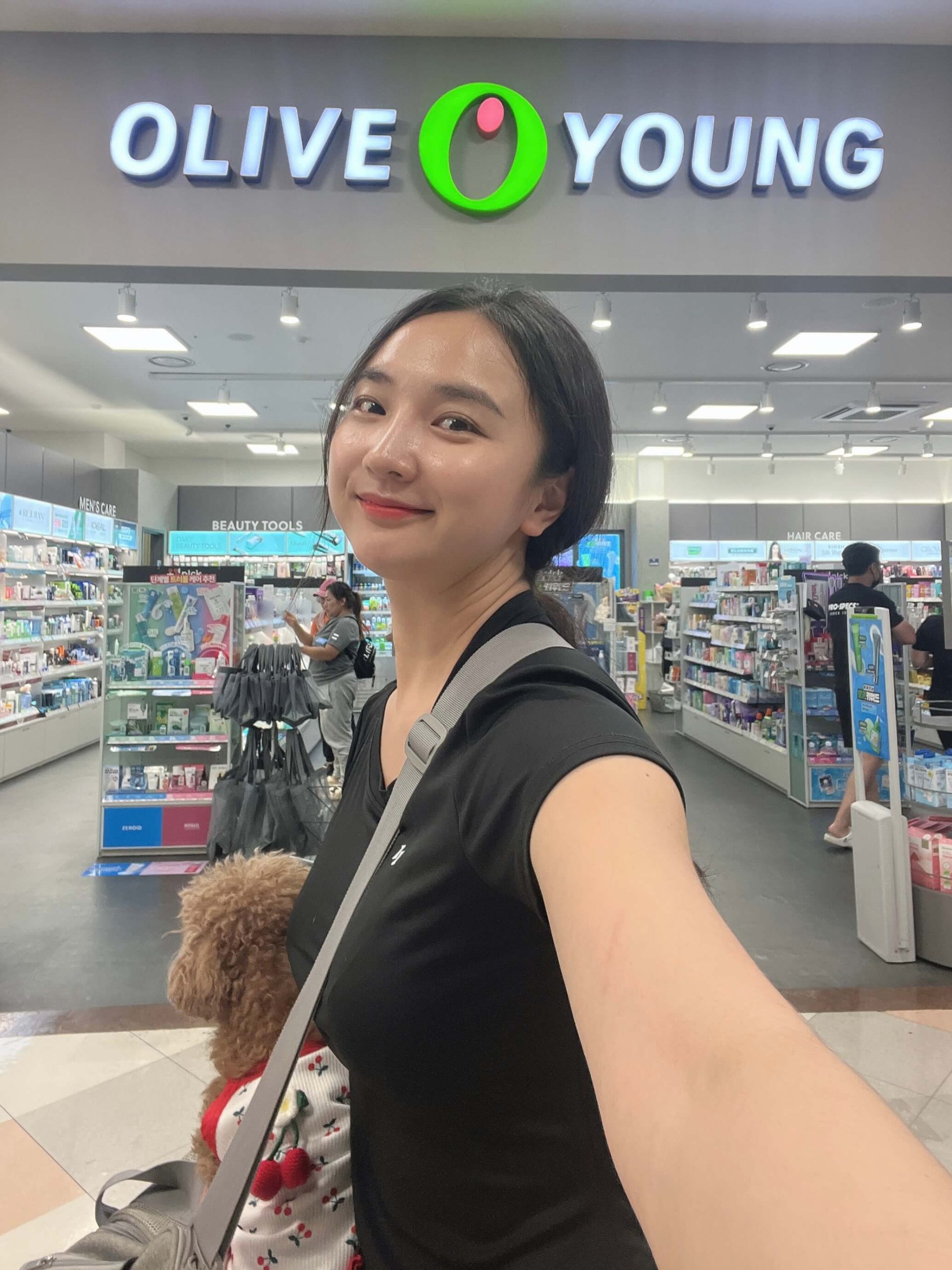 A photo of K-beauty expert Ggot-song holding a shopping bag, representing her guide to the top Olive Young must-buy items.