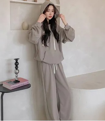 A K-Pop idol in a street style combo, pairing an oversized hoodie with wide pants and a bucket hat.
