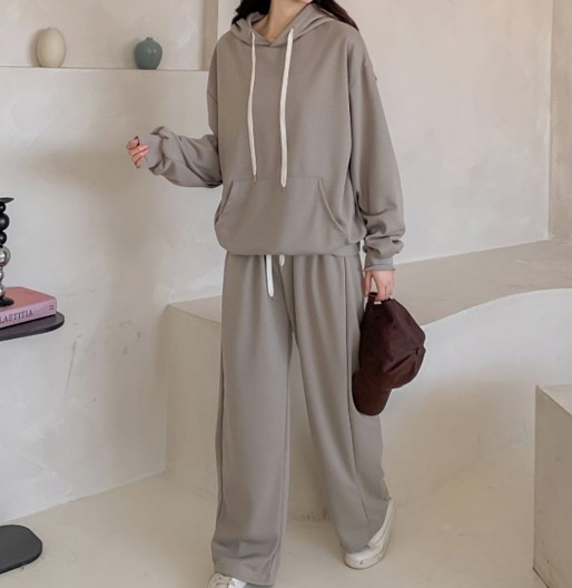 A K-Pop idol in a street style combo, pairing an oversized hoodie with wide pants and a bucket hat.